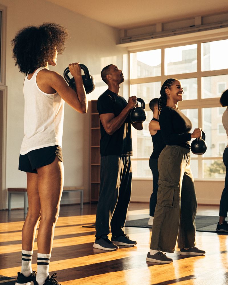 Small group fitness class with kettlebells in a bright studio